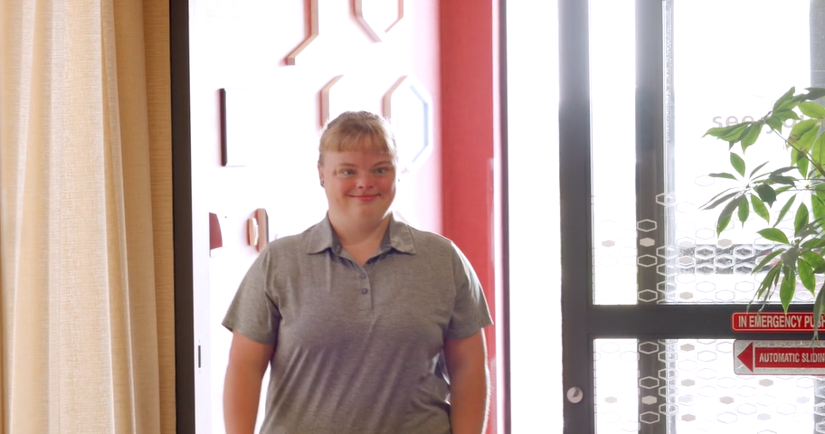 A woman with blond hair tied back is walking into her job as a hotel hostess.